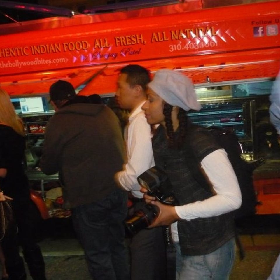 Crowd gathers at an Indian food truck beneath a sign advertising authentic Indian food and fresh ingredients.